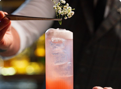 Bartender garnishing a pink gin cocktail