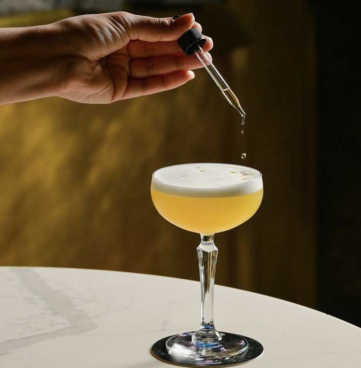 Drops of bitters being added to a cocktail